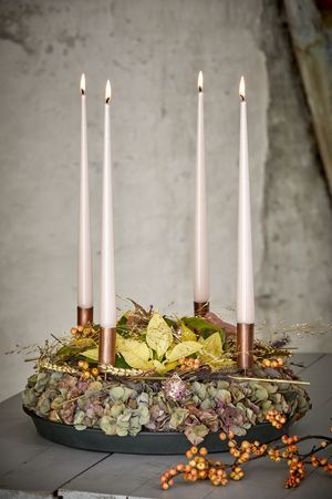 Schwarzes Tablett mit Adventskranz aus getrockneten Hortensienblüten, cremefarbenen Mini-Weihnachtssterne, Weihnachtskugeln, Gräsern, Ilex,  Getreideähren und vier weißen Kerzen in kupferfarbenen Kerzenhaltern