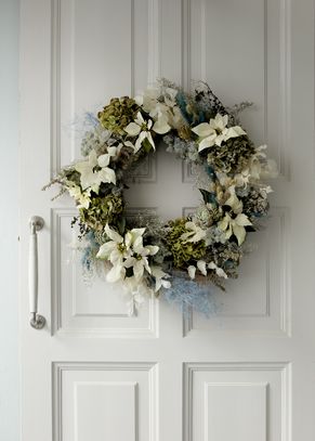 Wreath with white poinsettias and dried flowers hanging on door