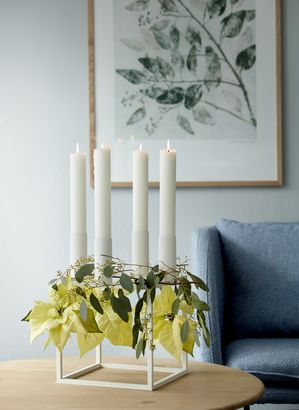 Moderne kandelaar met kerststerren en eucalyptustakjes op een salontafel