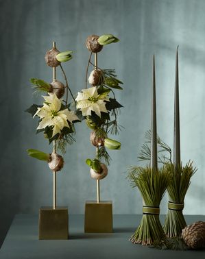 Stand with mounted mini poinsettias and hyacinth bulbs and candlestick holders made of pine needles.