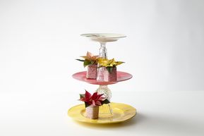 Homemade upcycled cake stand made of dinner plates, dessert plates, glasses and saucers with poinsettias