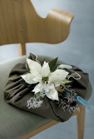 Gift wrapped with fabric and white poinsettia on chair