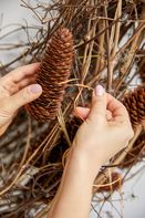 Hands fasten with wire cones to wreath with paper-covered binding wire